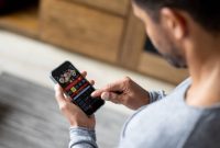 Man gambling online on a football match using his cell phone - lifestyle concepts